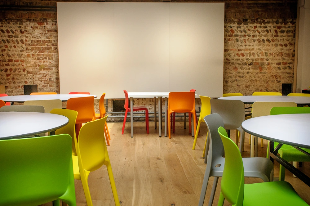 The interior of 68 Middle Street showing a warm inviting room with colourful chairs arranged around circular tables.